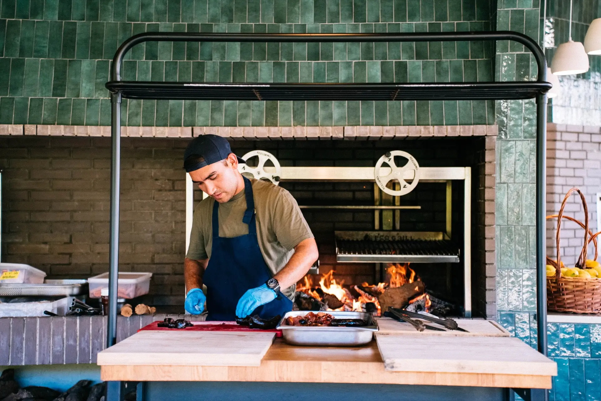 Cozinheiro a cortar carne na grelha a lenha da cozinha exterior