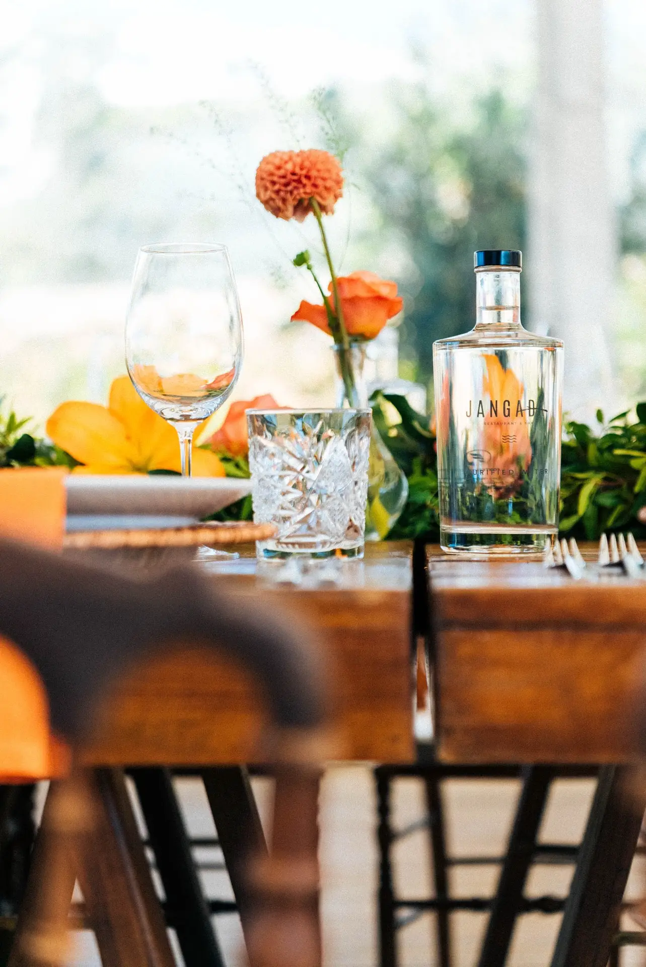 Garrafa de gin e copos numa mesa com flores