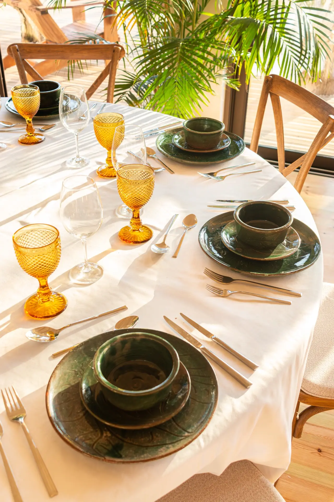 Mesa com loiça verde-garrafa e copos cor de âmbar