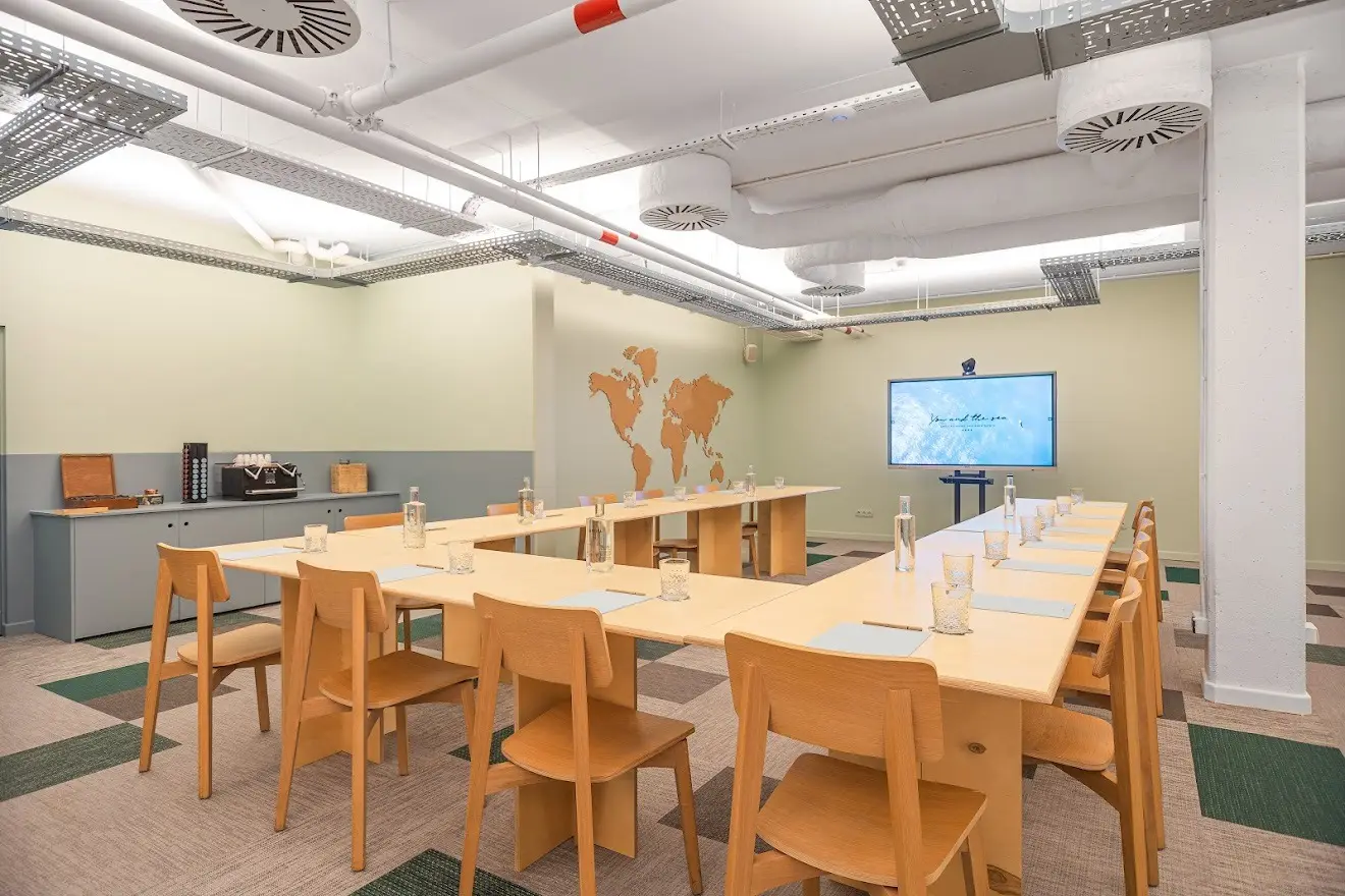 Sala de reuniões Octopus com mesas em U e um ecrã ao fundo
