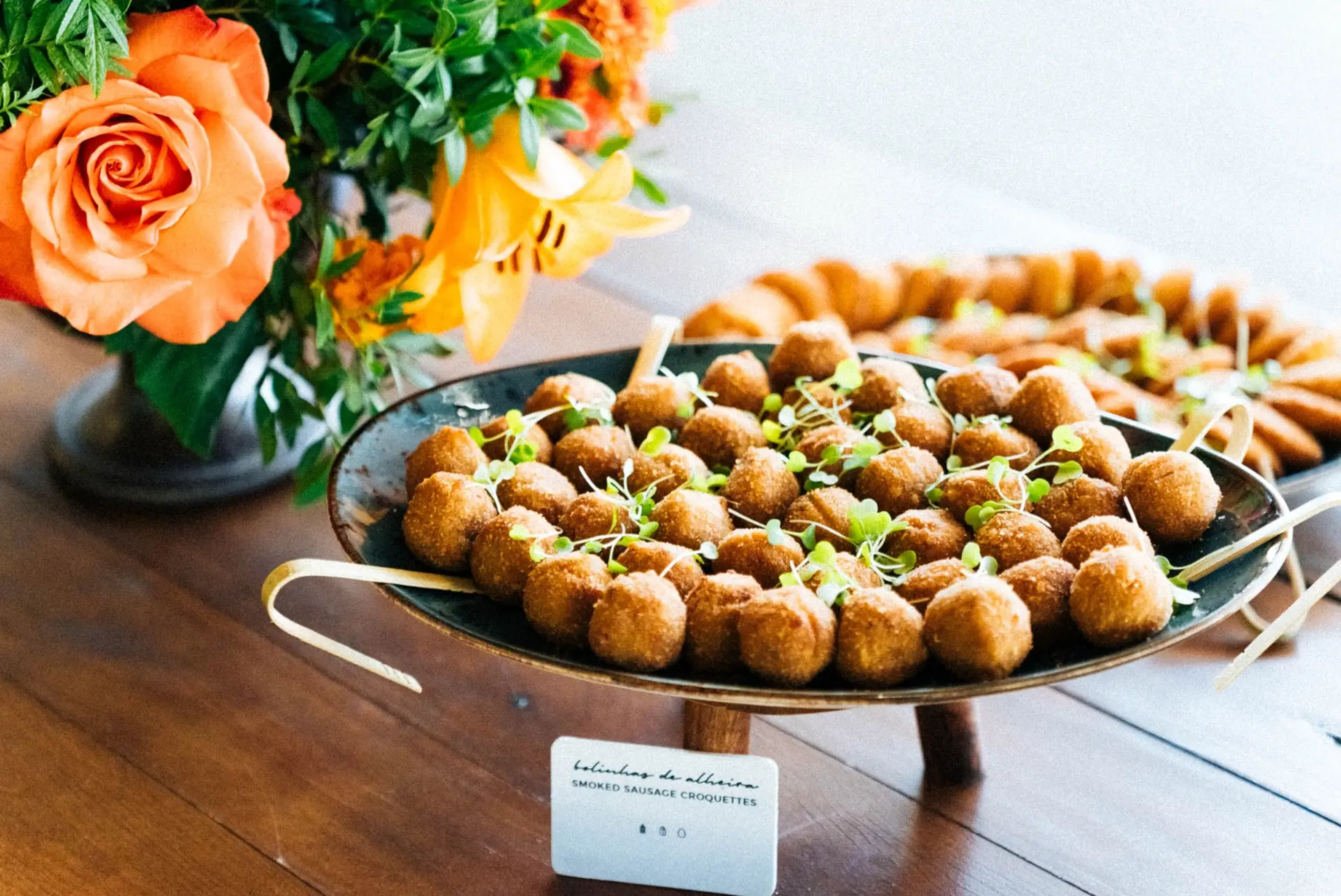 Travessa de croquetes com flores cor de laranja ao lado